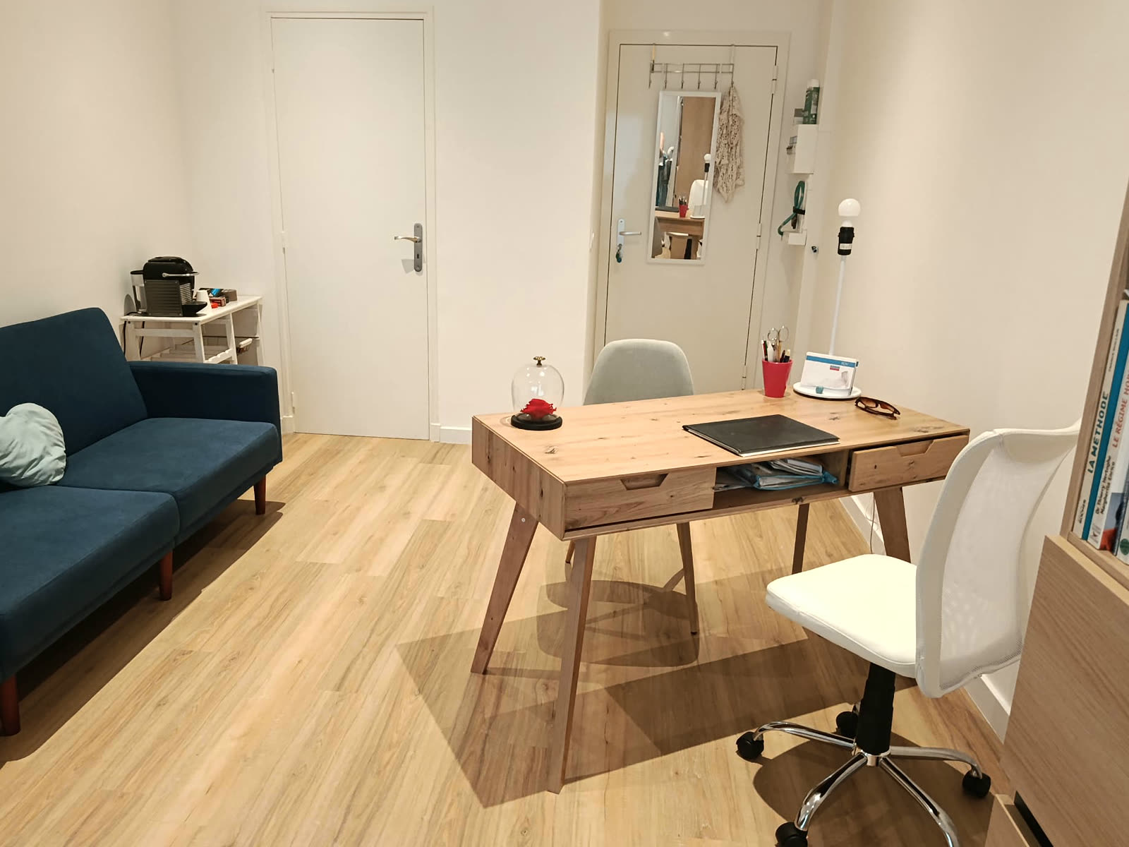 Le bureau de consultation, lumineux, avec canapé bleu et bureau en bois clair
